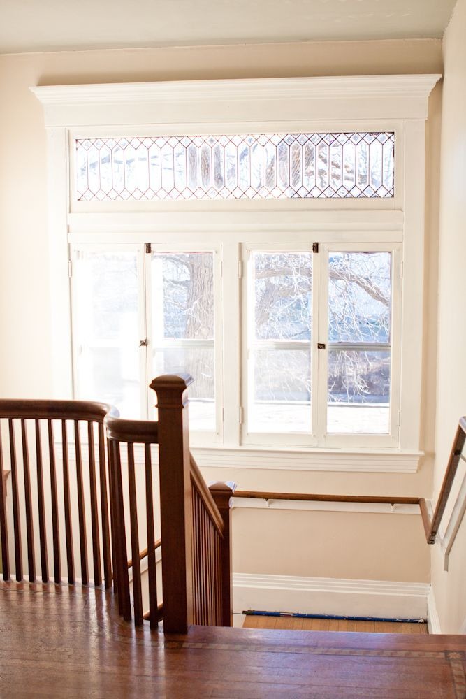 Staircase with vintage wood railing and decorative transom window
