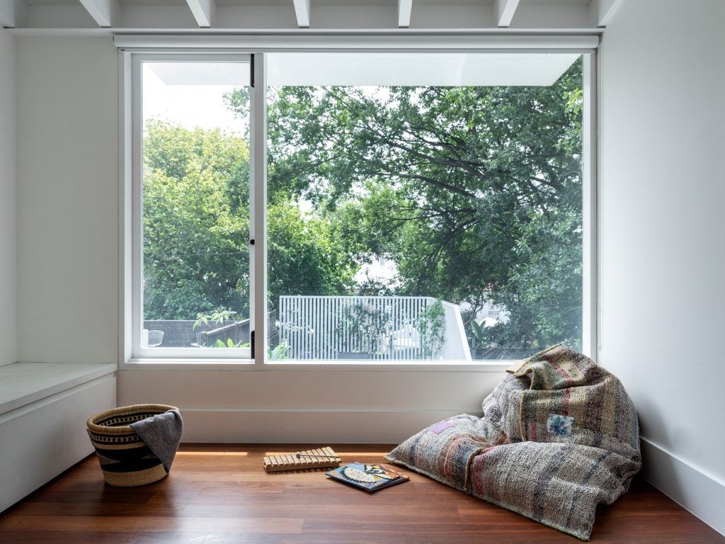 Large white sliding window with bright green outdoor garden view